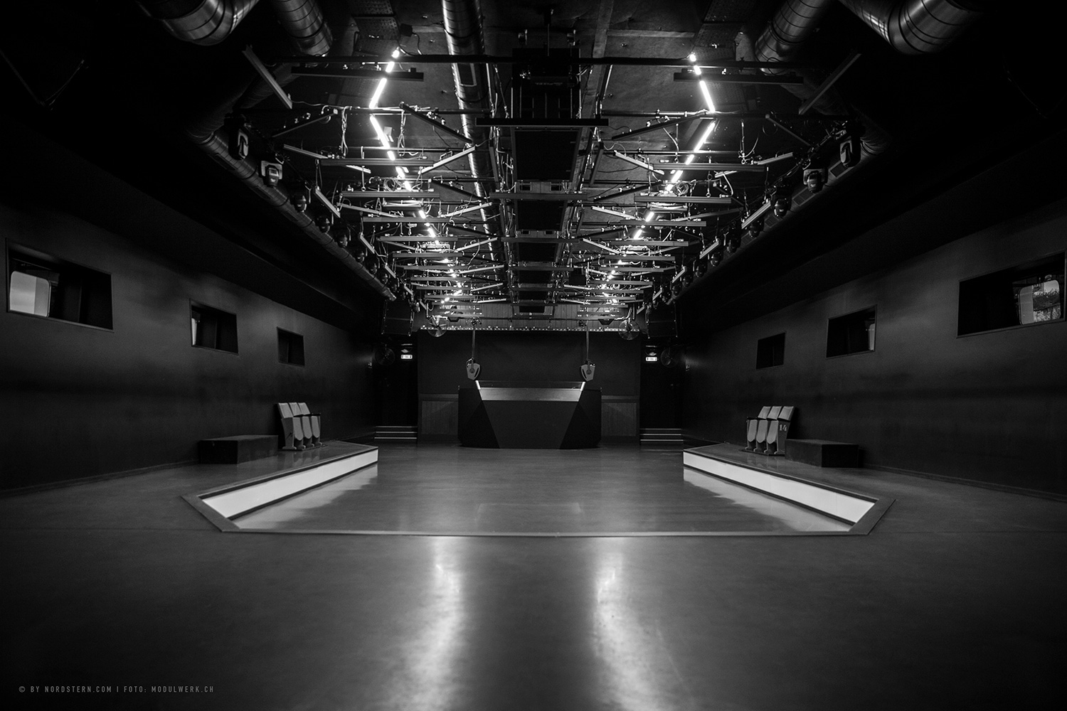 WSDG was in charge of the famous EDM nightclub Nordstern in Basel, Switzerland sound isolation, acoustics, and audio design inside the nightclub. Nightclub inside black and white DJ Booth.